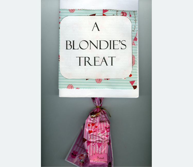 "A Blondie's Treat" appear in black letters on a white label over wrapping paper with a pink candy bag hanging below