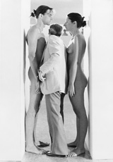 man standing between naked man and woman in doorway