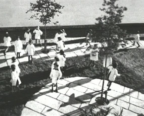 David Claerbout, video still, school children standing in courtyard with two small trees