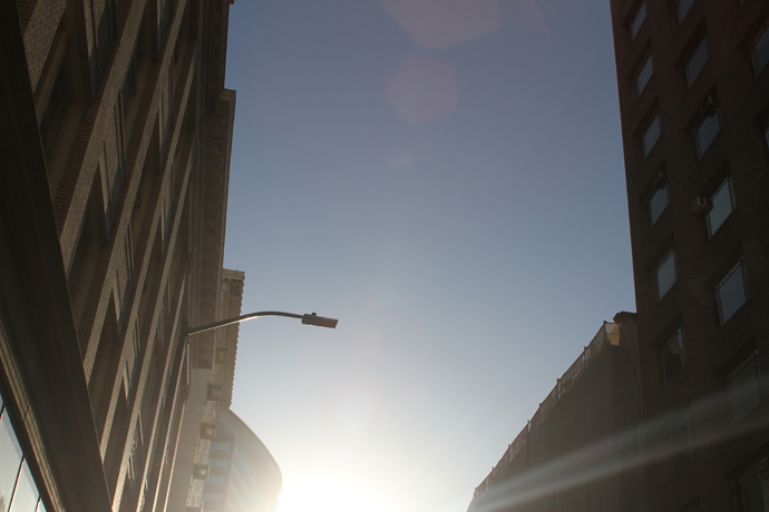 steet lamp sky and sun between two buildings from below