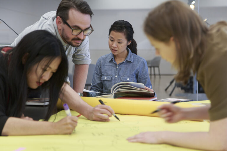 A group of adults write on a large roll of paper