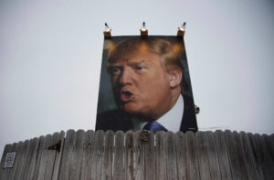 A photograph of a man with white hair is tacked to a wall above a wooden fence