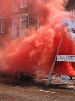 Red smoke envelops a car and a sign that says "Art"