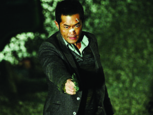 Man pointing a pistol at someone offscreen