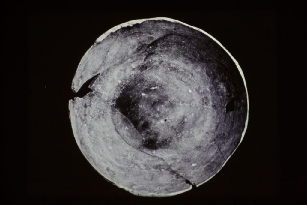A grey circle resembling a broken plate on a black background