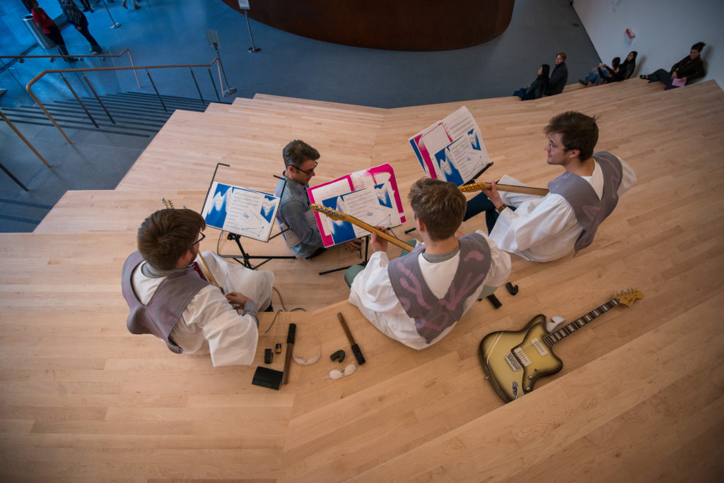 Performers with guitars playing music on a staircase