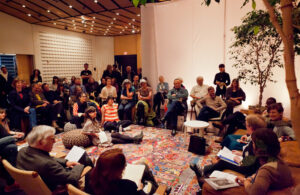 Semi-circle of speakers starting with Joe Goode, Joshua Kit Clayton, Barry Jenkins, Margaret Tedesco, Terry Castle, Lindsey Boldt, Marion Gray, Richard O. Moore. On poofs in center of the room: Georgie Devereaux, Amy Trachtenberg, Dana Cohen.