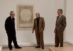 Three Caucasian men stand before a painting in a gallery, Rauschenberg